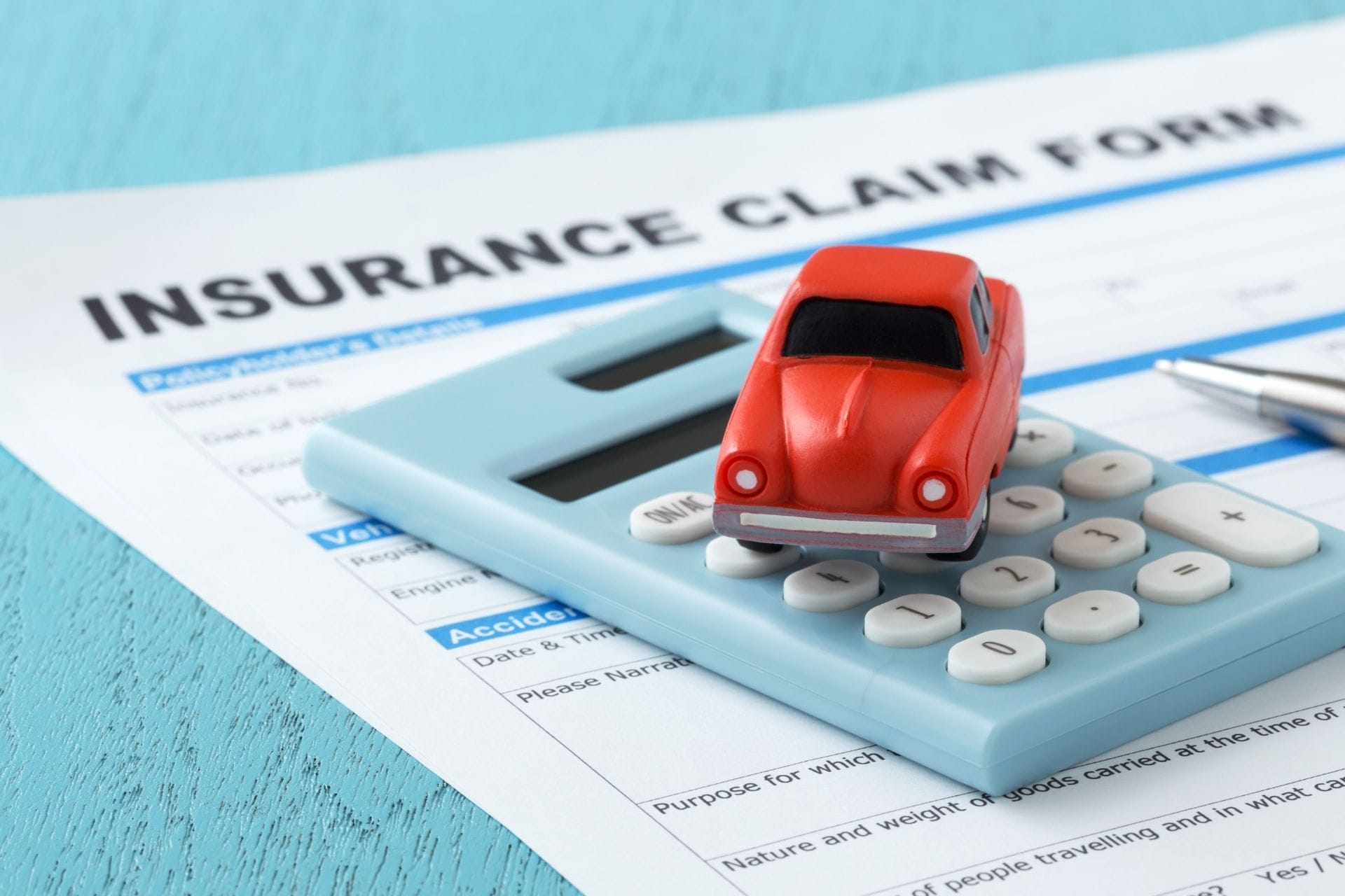 red car and calculator on insurance form